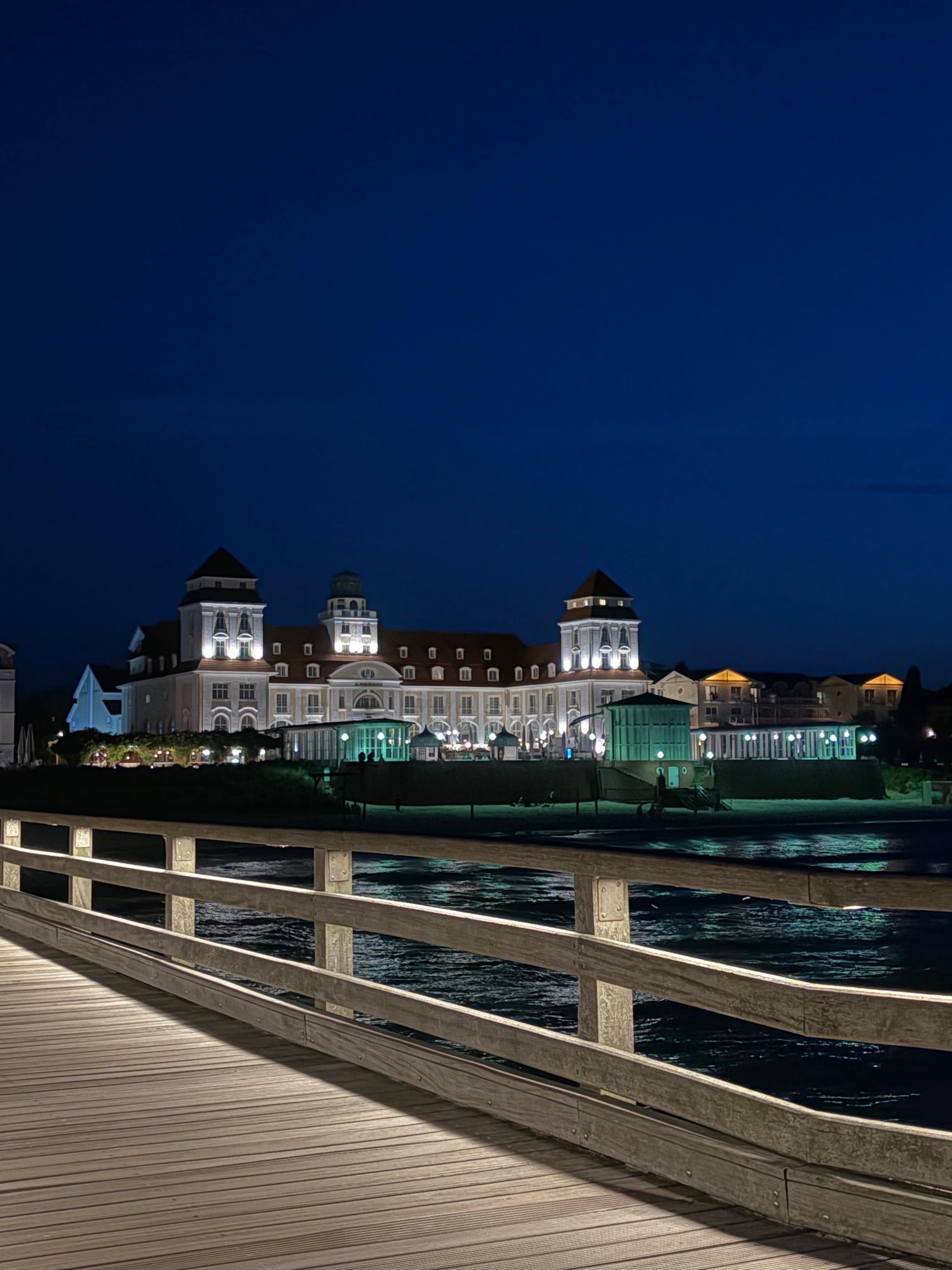 Das beleuchtete Kurhaus Binz, von der Seebrücke aus gesehen