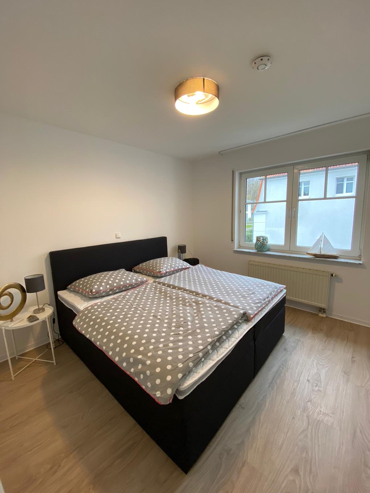 Elternschlafzimmer mit schwarzem Boxspringbett und Blick ins Grüne