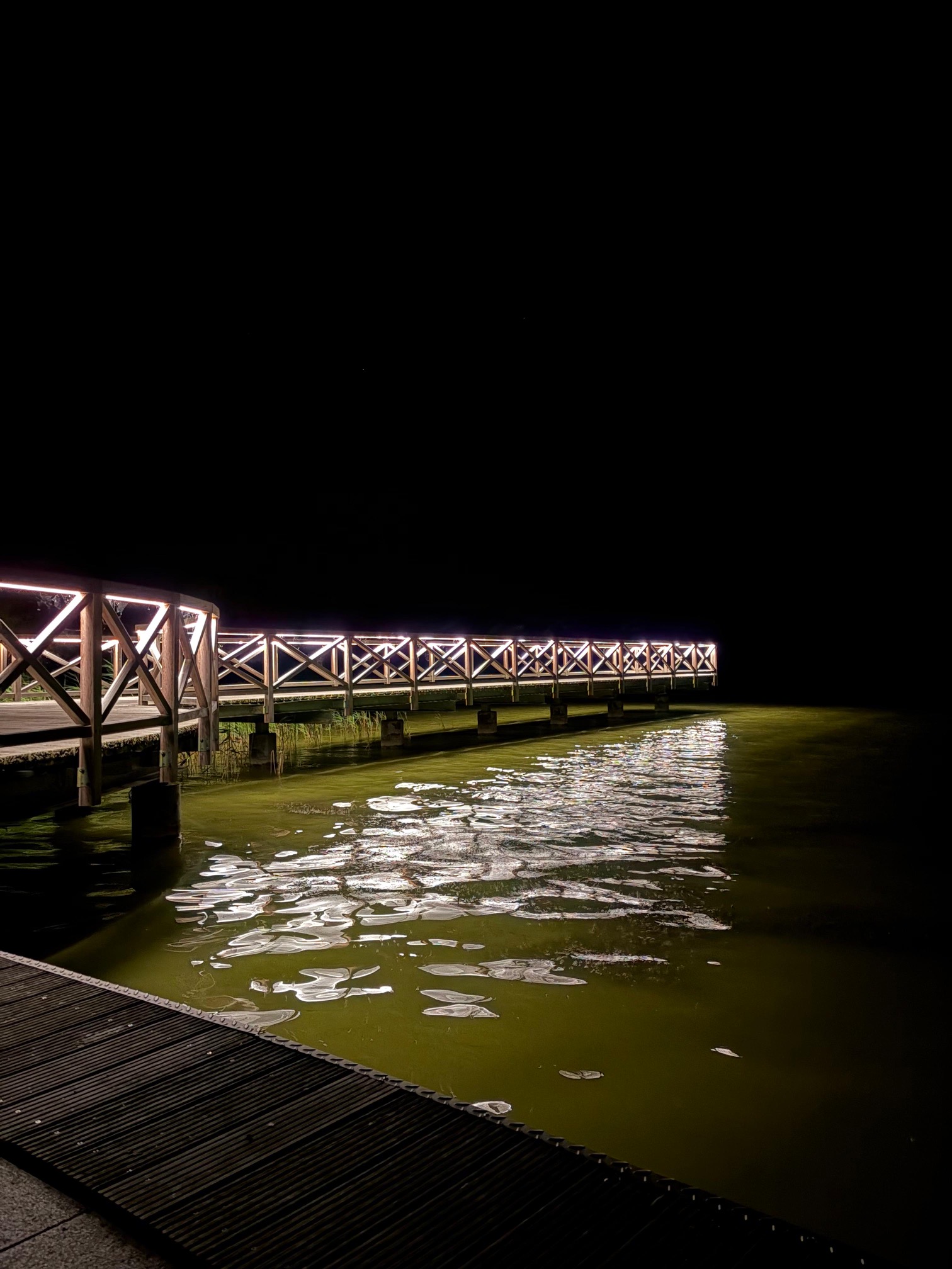 Beleuchteter Holzsteg am Schmachter See bei Nacht